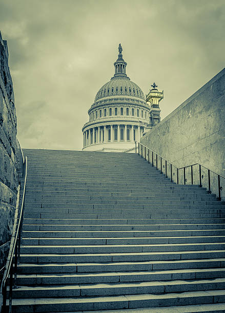United States Capitol This photo was taken on 17 November 2013 on a cloudy gloomy day in Washington D.C.  This is a picture of the United States Capitol building.  This picture has an intentional green money tint to represent the greed of our nations leaders, the same as the greed of money.  The stairs represent the climb to the top of power.  While the Capitol building represent the corruption of the American government. capitol building washington dc photos stock pictures, royalty-free photos & images