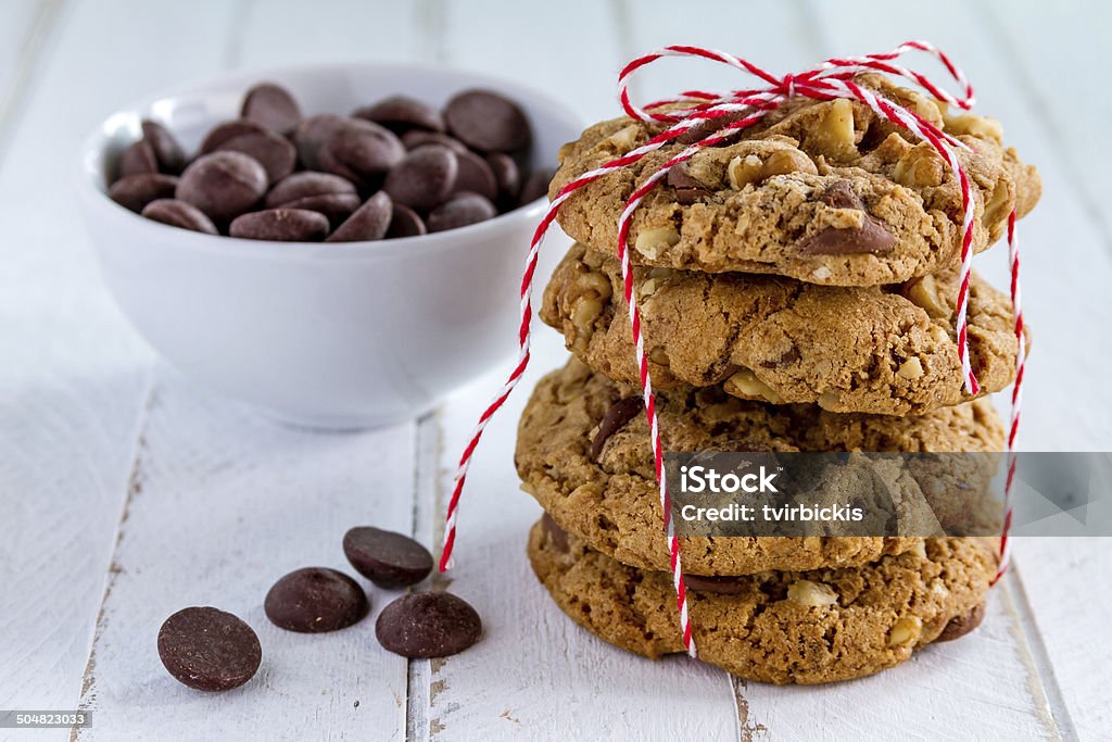 Homemade Chocolate Chip Cookies with Walnuts Stack of homemade chocolate chip cookies tied with red bakers twine and bowl of dark chocolate chips Baked Stock Photo
