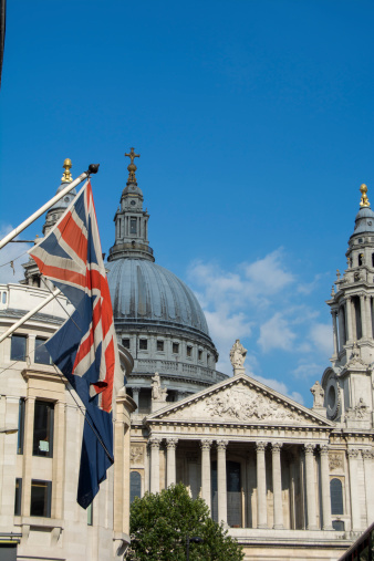 vertically composed view of st. paul's cathedral from fleet street, london, england with flag (union jack) and red london bus in foreground