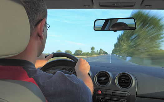 Interior car image of a man driving.Main focus is on the board.