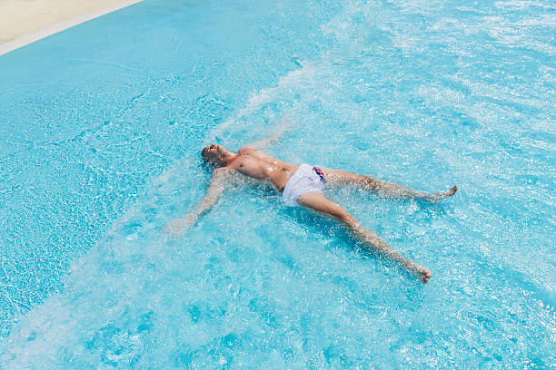 istock Young Man Lying on Back in Shallow Waves of Pool 504825456