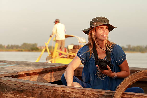 vietnamese senior woman sitting at boat deck and waving to camera  on floating market in Can Tho, south vietnam