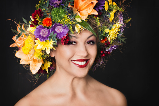 Portrait of happy mid aged woman wearing colorful wreath of flowers.