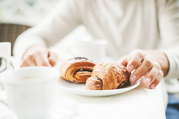 istock Man in a cafe having a coffee break with croissants 504854203