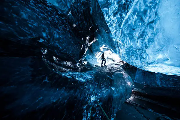 Inside an icecave in Vatnajokull, Iceland. A climber silhoutted against the ice. The ice is thousands of years old and so packed it is harder than steel and crystal clear. These caves are formed by meltwater that rushes from over and underneath the glacier and creates these wonderful sights