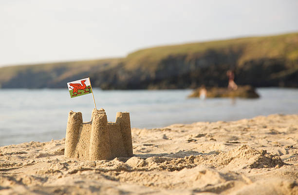 castillos de arena en la playa, mar, y bandera de gales - welsh flag fotografías e imágenes de stock