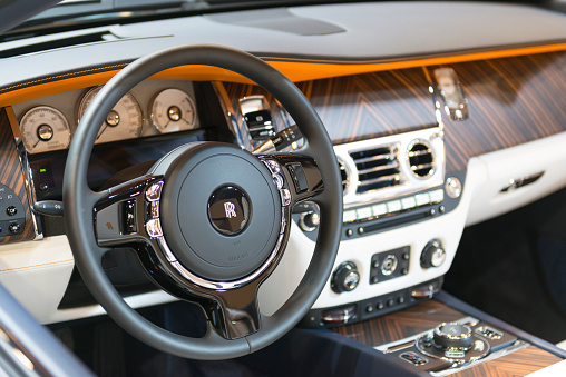 Brussels, Belgium - Januari 12, 2016: Wooden dashboard on a Rolls-Royce Dawn luxury convertible automobile. The car is fitted with a twin-turbo 6.6-litre V12 and luxurious leather and wood interior. The car is on display during the 2016 Brussels Motor Show. 