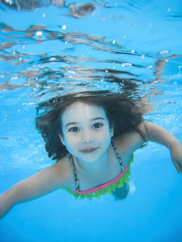 A little girl swimming and taken from underwater