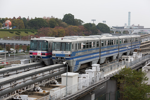 Osaka, Japan - November 23, 2015: Osaka Monorail Trains move past the Banpaku-Kinen-Koen in Suita, Osaka, Japan. It serves as the station for the Expo Commemoration Park and LaLaport EXPOCITY.