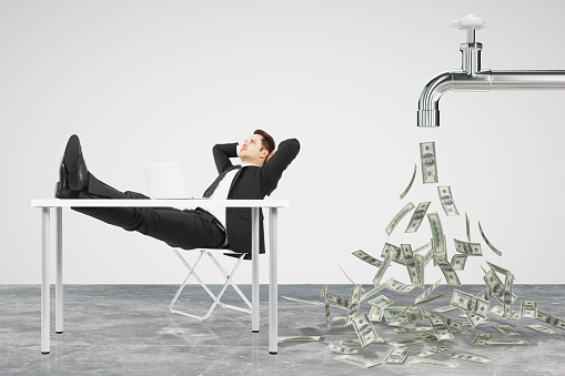 Businessman resting on a chair and faucet from which the money flow