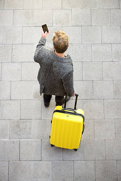 Traveling man walking with mobile phone ad suitcase Top view traveling man walking with mobile phone ad suitcase walking loneliness one person journey stock pictures, royalty-free photos & images