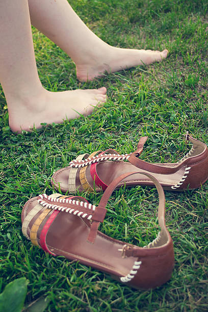 istock Bare female legs on grass near stand sandals. tinted 504875698