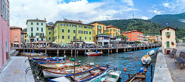 Torbole, Italy - August 2, 2015: Lake Garda boardwalk with houses, tourists and boats in Torbole, Italy. Torbole is one of the most popular towns on Garda Lake, known as a wind surfers paradise.