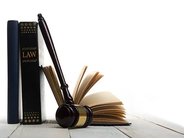 Photo of Open law book with wooden judges gavel on table in