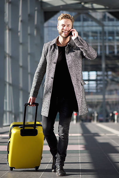 istock Smiling travel man walking with mobile phone and suitcase 504878034