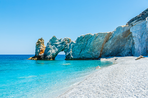 Summer holiday concept with a happy family lying on a beautiful beach with emerald sea, Cyclades, Greece