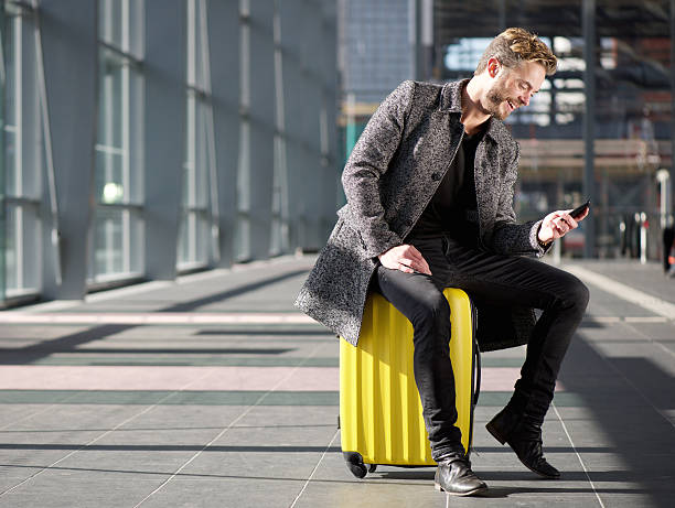 Smiling man resting at airport with mobile phone