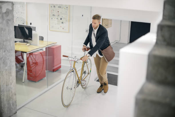 Businessman and his bicycle Young businessman arriving at work, pushing his bicycle top view on people walking and cyclists riding stock pictures, royalty-free photos & images
