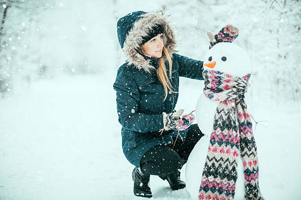 Young woman building snowman