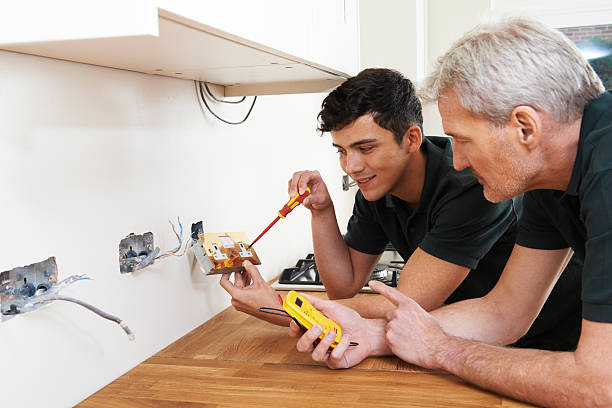 Electrician With Apprentice Working In New Home Electrician With Apprentice Working In New Home electrician smiling stock pictures, royalty-free photos & images