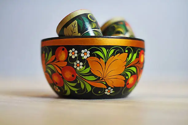Russian wood painting handicraft style and national ornament, Khokhloma, known for its vivid flower patterns, red and gold colors over a black background.