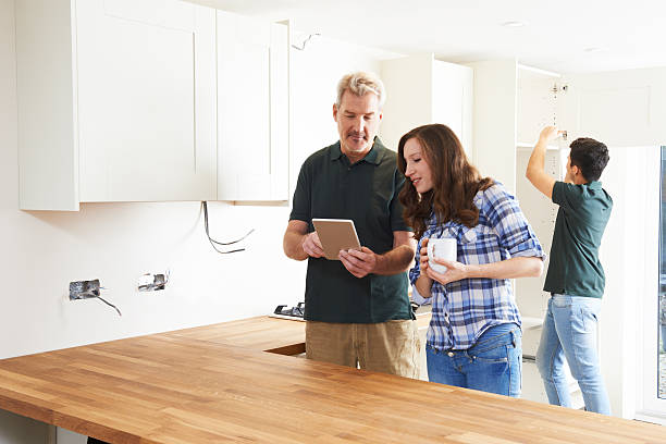 istock Woman With Carpenter Looking At Plans For Kitchen 504888636