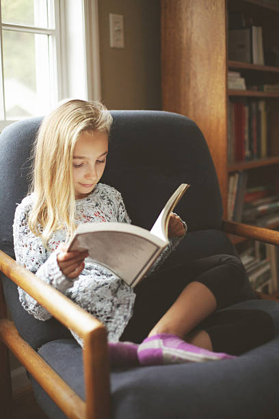 istock Elementary age girl reading a book indoors 504889546