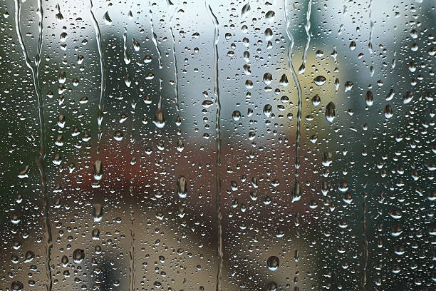 istock Rain drops on window with house and church in background 504891726