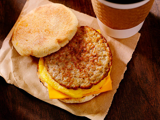 Sausage and Egg Breakfast Sandwich Sausage, Egg and Cheese Breakfast Sandwich on a Toasted English Muffin with a Take Out Coffee- Photographed on Hasselblad H3D2-39mb Camera english muffin stock pictures, royalty-free photos & images