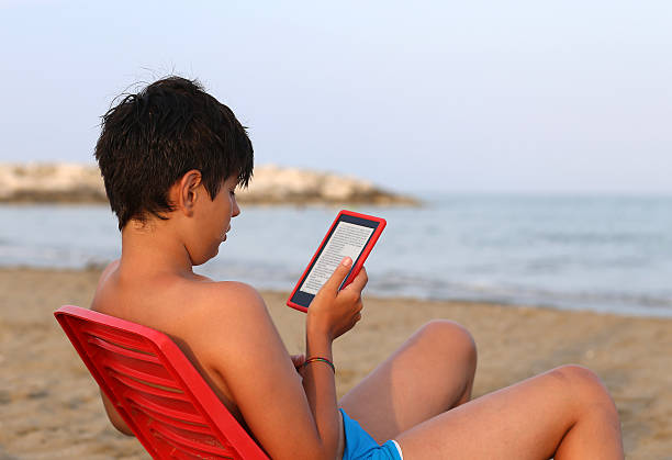 istock alone boy with hair blacks reads an e-book 504896078