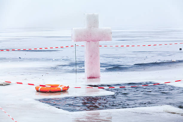 Ice cross and hole in winter pond on Epiphany Ice cross hole and an orange life preserver at the celebration Epiphany overcast winter day julian california stock pictures, royalty-free photos & images