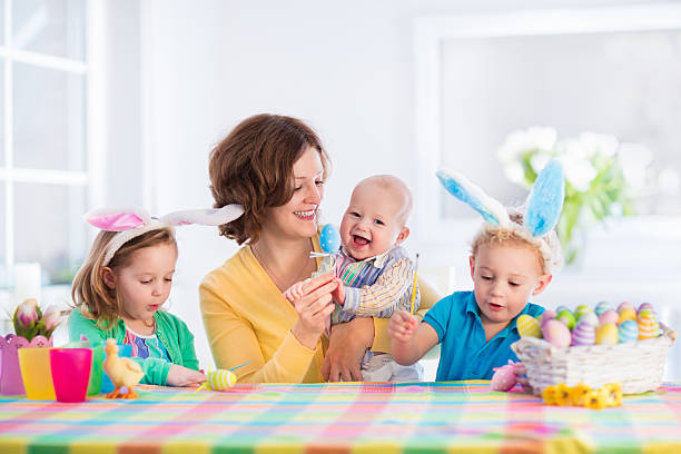 istock Mother with three children painting Easter eggs 504903178