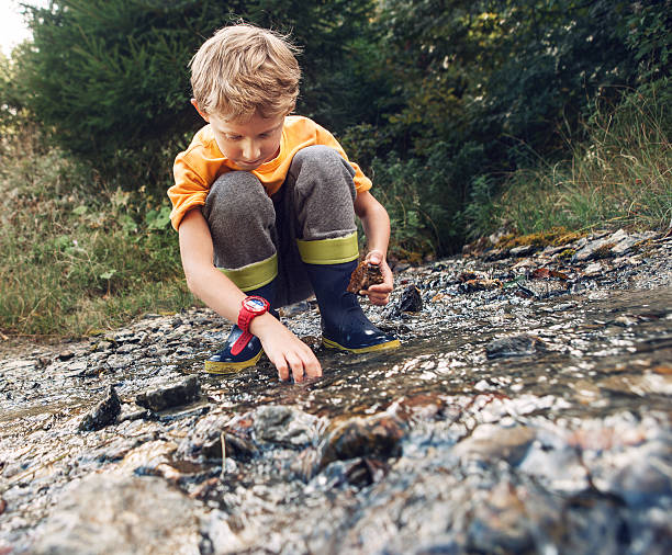 istock Boy in gum boots playing the into te forest stream 504903322