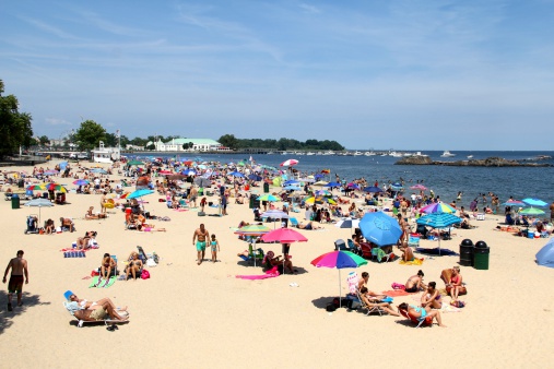 Rye Beach, NY, United States - June 29, 2014: A crowded beach full of beach-goers enjoying the hot summer sun while relaxing on Rye beach at Play-Land Park in Rye New York.