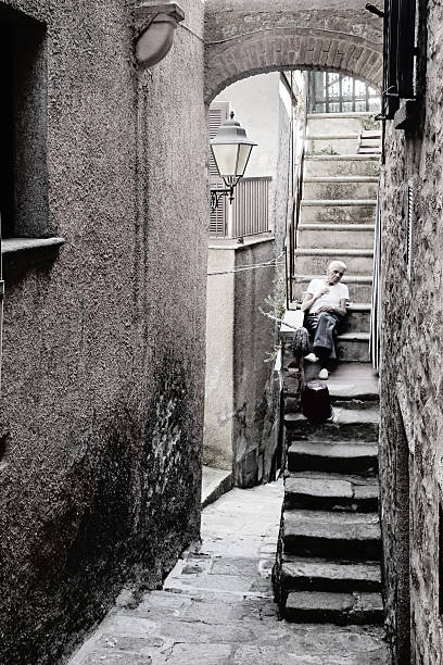 Giglio Island, Italy - July 19, 2014: Old man is resting on the stairs of the house in Ancient Village \