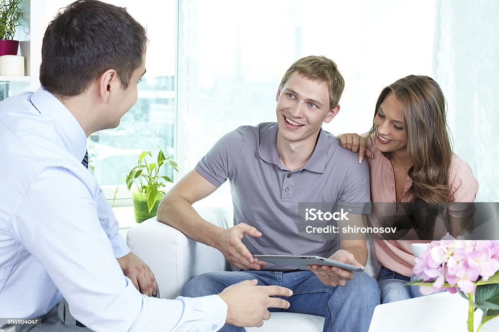 Modern planning Businessman showing a business plan or insurance program on the screen of the pad to the young people Adult Stock Photo