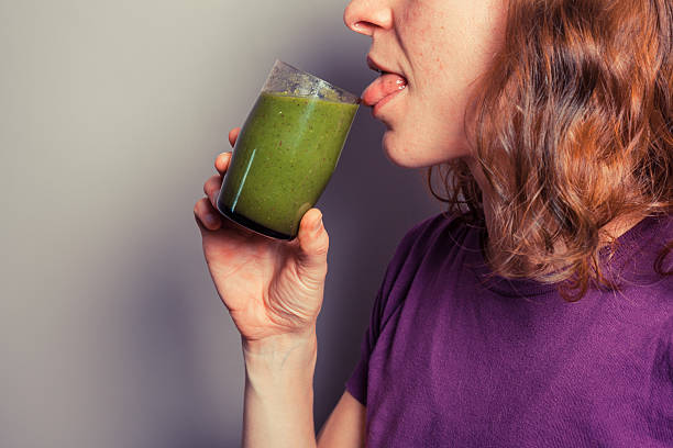 istock Young woman drinking green smoothie 504904159