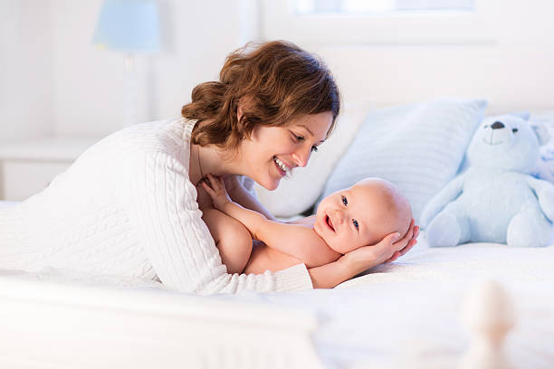 Mother and baby on a white bed stock photo