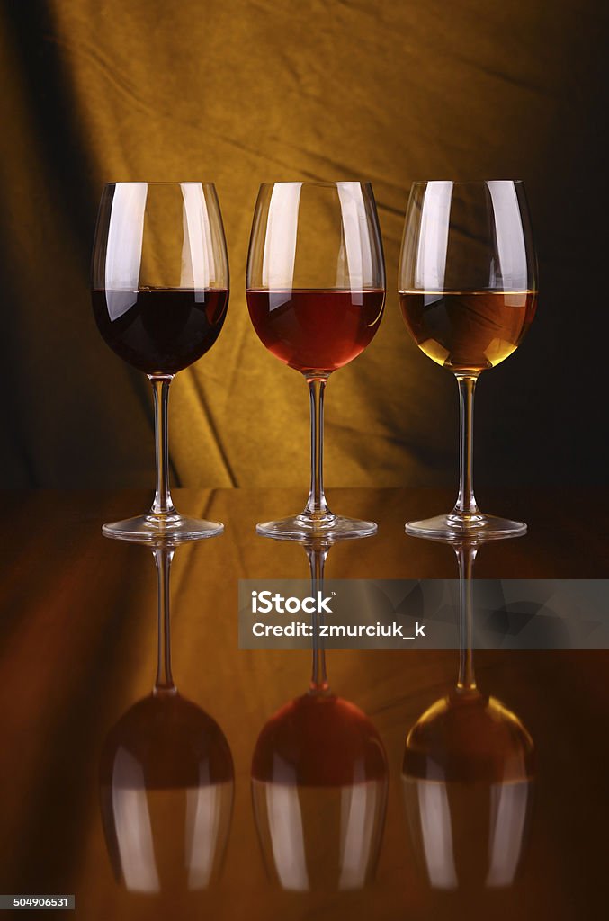 Wine glasses Glasses of red, rose and white wine over a draped background lit yellow Alcohol - Drink Stock Photo