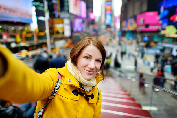 красивая женщина, получающих селфи на таймс-сквер - new york city times square crowd people стоковые фото и изображения