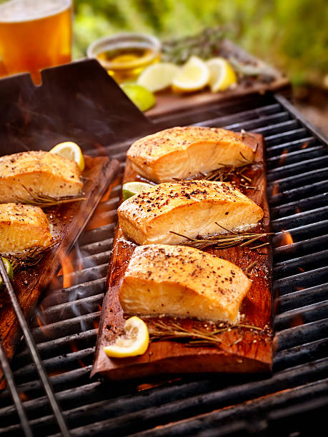 filet de saumon sur planche de cèdre un barbecue en extérieur - broiled fish photos et images de collection