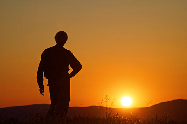 istock Man watching the sunset on a grassy horizon. Silhouette. 504908772