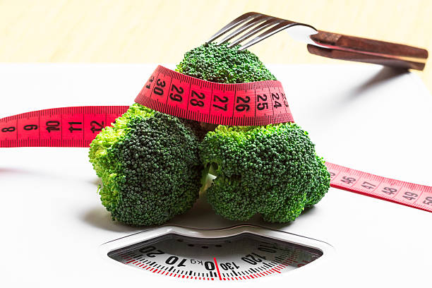 istock Broccoli with measuring tape on weight scale. Dieting 504912146