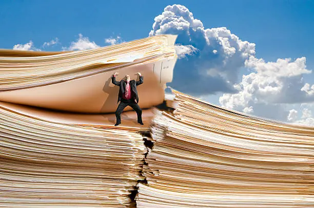 Photo of Business man holding a giant pile of files