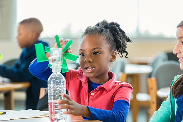 Students studying alternative wind energy during elementary science class African American and Hispanic elementary age little girls are students in public elementary school after school science club program. Girls are using water bottles to create small windmills while studying alternative wind energy. science class stock pictures, royalty-free photos & images