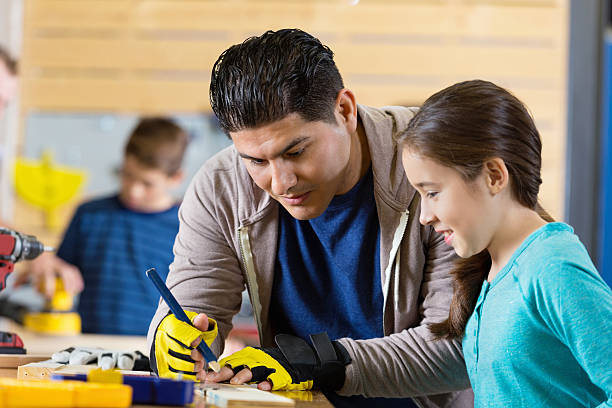 istock Father teaching daughter to build something in workshop or garage 504919462