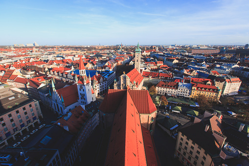 Beautiful super wide-angle sunny aerial view of Munich, Bayern, Bavaria, Germany with skyline and scenery beyond the city, seen from the observation deck of St. Peter Church
