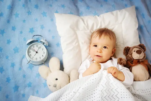 Photo of One year old baby with alarm clock