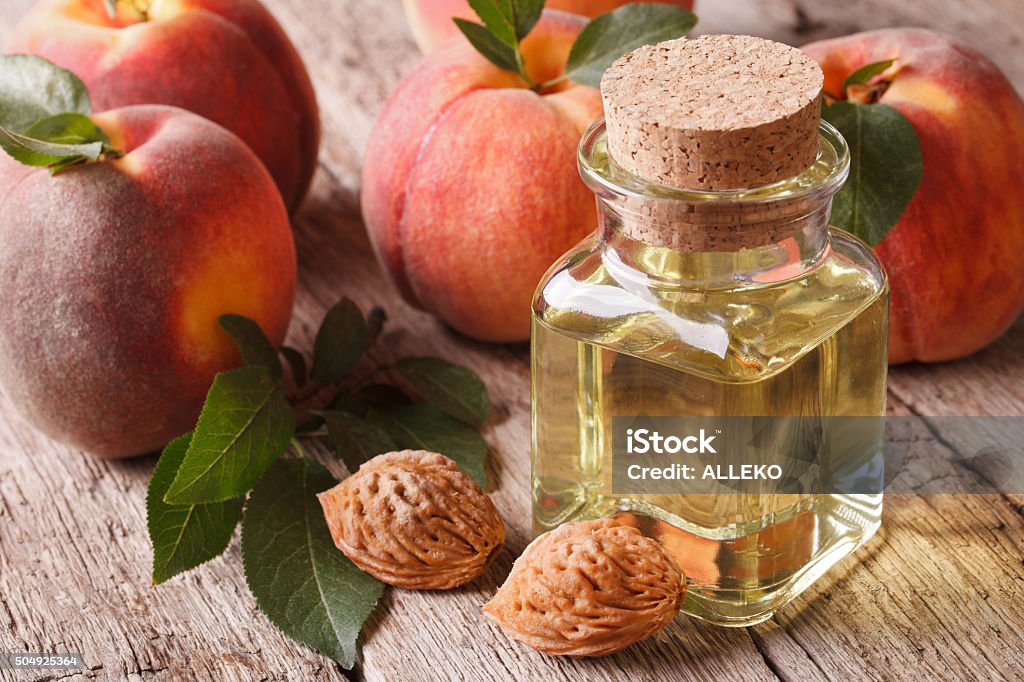 Cosmetic oil peach in a glass bottle on table closeup Cosmetic oil from kernels of peach in a glass bottle on a table close-up. horizontal Beauty Stock Photo