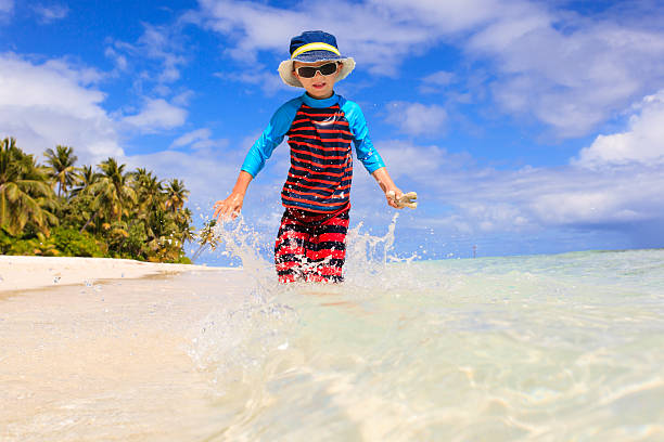 istock little boy running splashing water on beach 504930034